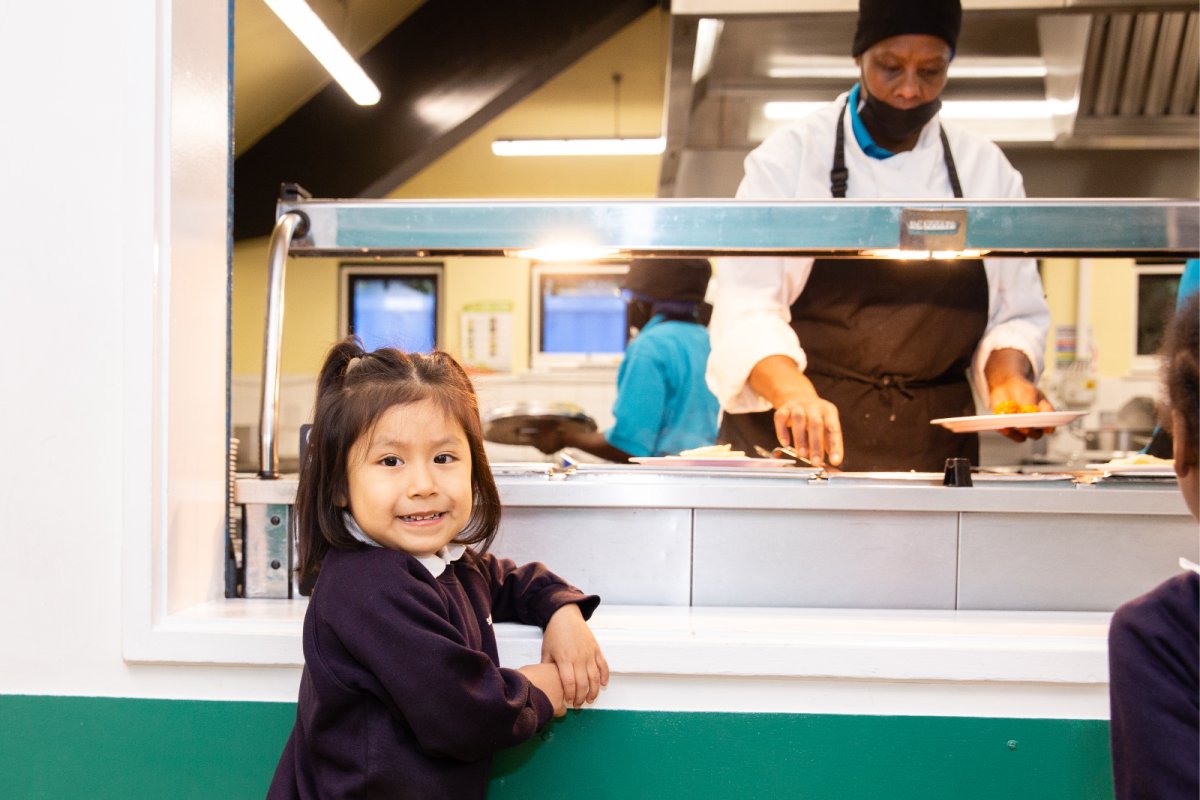 Primary school child waiting at canteen counter to receive her school meal. Credit: 