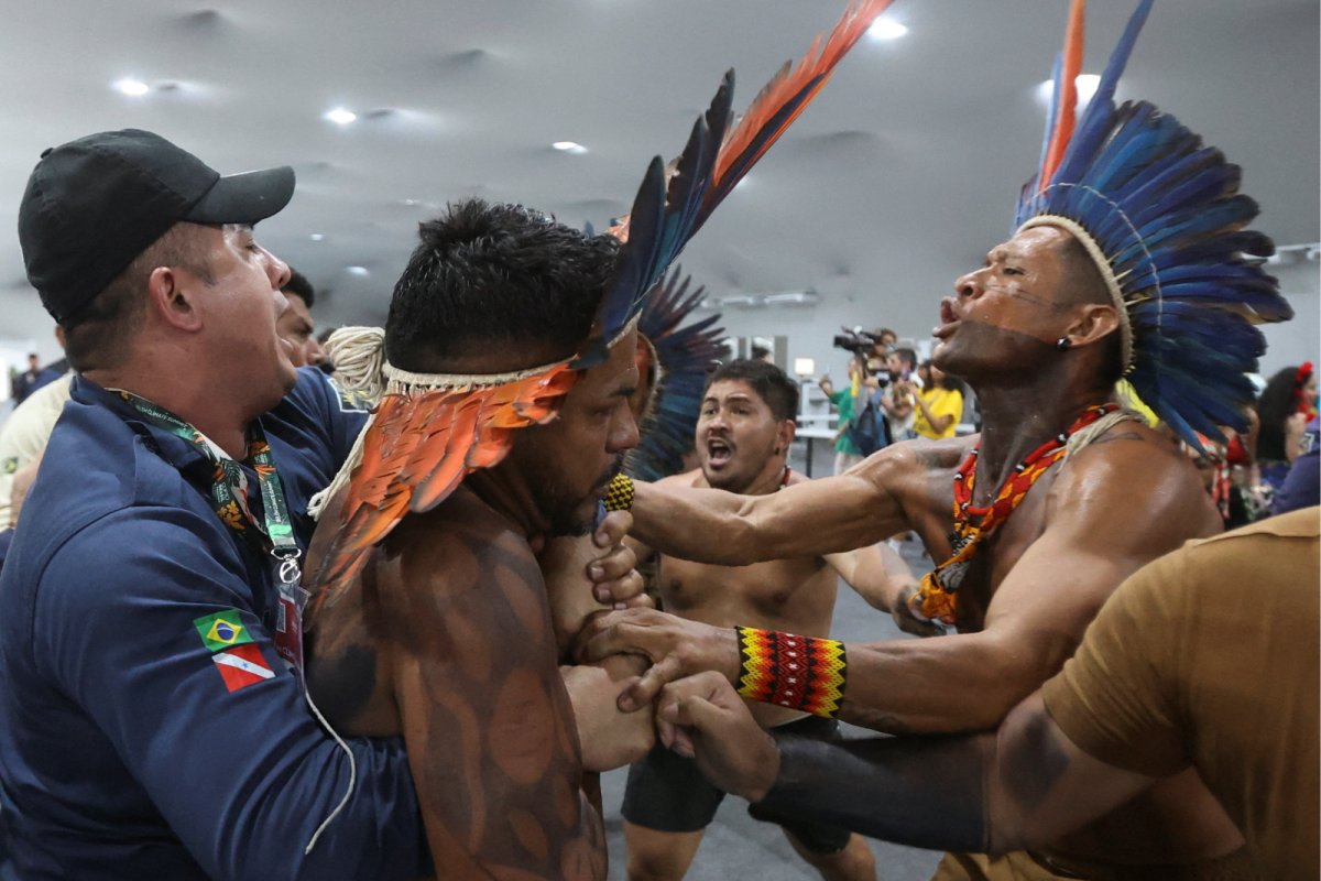 An Indigenous demonstrator is held by a staff member as protesters forced their way into the venue hosting the UN Climate Change Conference (COP30), in Belem, Brazil, November 11. Credit: Anderson Coelho | Reuters 