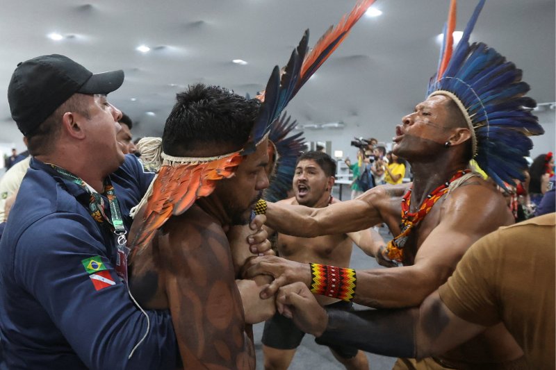An Indigenous demonstrator is held by a staff member as protesters forced their way into the venue hosting the UN Climate Change Conference (COP30), in Belem, Brazil, November 11. Credit: Anderson Coelho | Reuters 