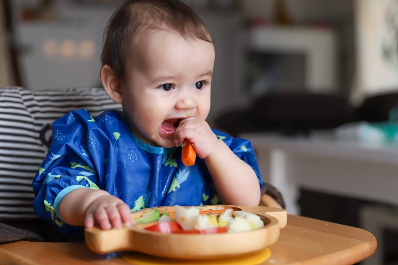 Baby eating finger food from mixed vegetable plate. Copyright: Onjira Leibe | shutterstock