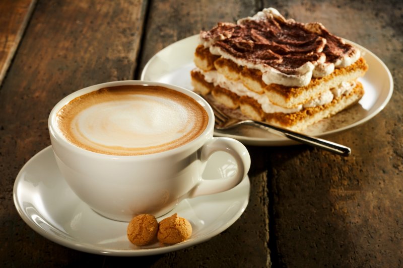 Cup of double espresso coffee with piece of cake on wooden table. Copyright: stockcreations: Shutterstock
