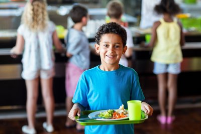 Schoolboy holding food tray in canteen. Copyright: wavebreakmedia | shutterstock