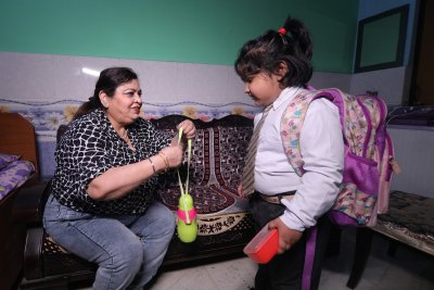 Woman giving water bottle to a child. Credit: World Obesity Federation