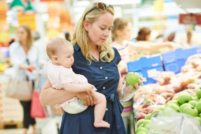 A woman with baby shopping for fruit. Copyright: Dmitry Kalinovsky | Shutterstock