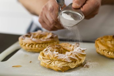 Pastry chef dusting freshly made Paris-Brest with icing sugar at the Cookery School. Credit: The Cookery School