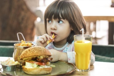A child eating a burger and fries at a restaurant. Credit: PV Productions: Shutterstock