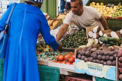 Woman buys fresh fruits and vegetables from a market stall at Brixton Market. Credit: Alena Veasey / Shutterstock