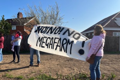 Local campaigners in Methwold hold up 'No! No! No! Megafarm!' banner to protest proposed megafarm . Credit: Lily O'Mara