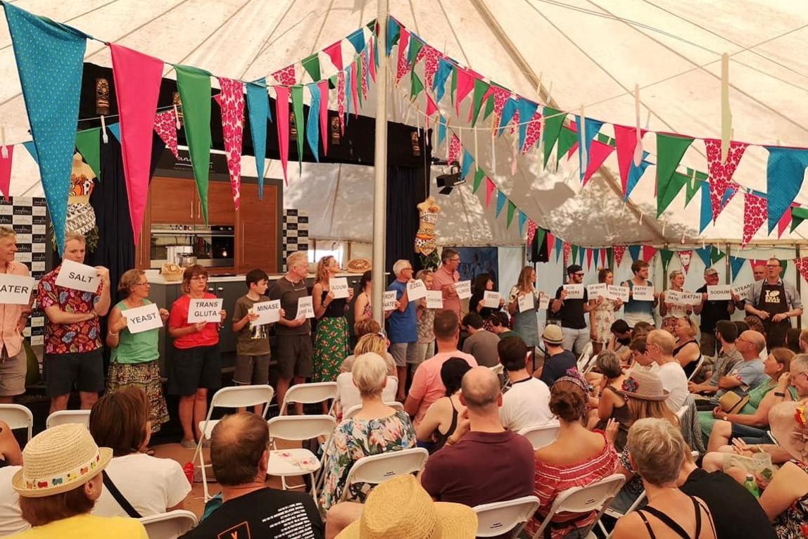 Chris Young shows a packed tent just some of the stuff that may be used in an industrial loaf. Photo © The Theatre of Food